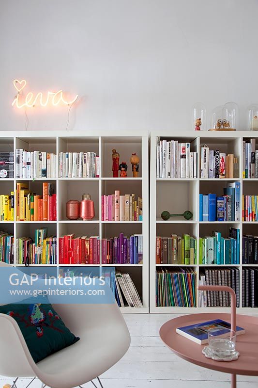 Große Bücherregale mit Büchern nach Farben und Neonkunst