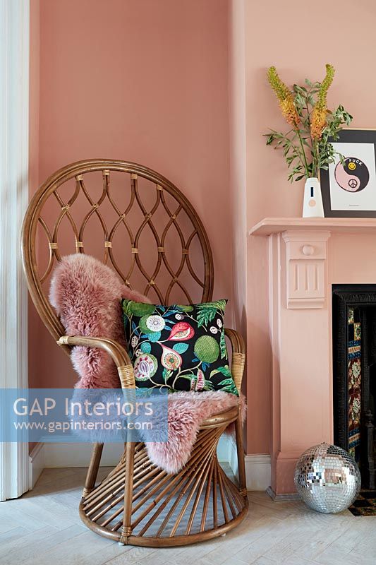 Korbsessel mit hoher Rückenlehne im pink gestrichenen Wohnzimmer