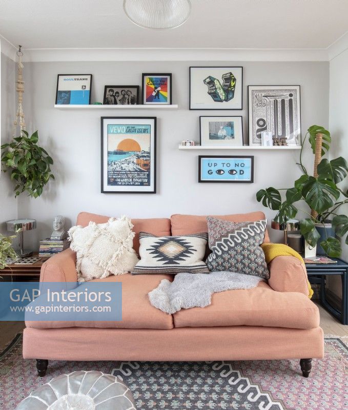 Ausstellung von Kunstwerken über dem lachsfarbenen Sofa im modernen Wohnzimmer