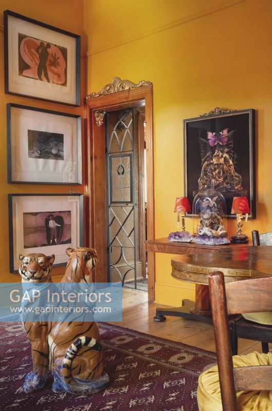 Doorway to living room with art on walls and ceramic tigers on rug
