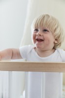 Lächelnder kleiner Junge im Kinderbett im Kinderzimmer