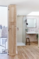 Ensuite-Badezimmer mit offenem Schnitt, Dusche und Waschbecken, Holzdielenboden, Oberlicht und Blick über die Dächer