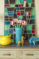 Auf einer Art-déco-Truhe befindet sich ein Buntglasfenster, eines von zwei, die die Durkins auf Craigslist gekauft haben. Zu sehen sind ausgewählte Beispiele italienischer Keramik, darunter ein blauer Rimini-Stier von Aldo Londi für Bitossi.