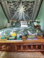 Ein großes Bettdeckenset mit Blattwerk und ein niedriger Rattantisch verleihen dem Schlafzimmer eine tropische Atmosphäre.