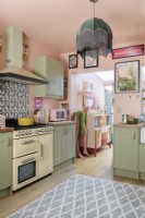 Eine blassrosa und grüne Retro-Küche im Shaker-Stil mit Blick durch den Wintergarten