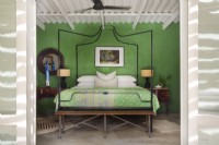 Schlafzimmer mit Himmelbett aus Metall und grüner Wand
