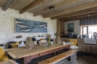 Große und komfortable rustikale Küche mit hölzernem Bauerntisch und großem modernen Kunstwerk von Fischen in einem blauen Meer.