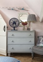 Grau lackierte Holzkommode im rosafarbenen Schlafzimmer