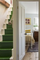 Grün gestrichene Treppe und Blick vom Treppenabsatz auf das Schlafzimmer