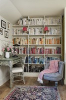 Wand aus Bücherregalen im kleinen Lesezimmer mit Schreibtisch und Sessel