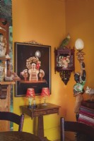 Esszimmerecke mit gelber Wand, eklektischen Ornamenten und Kunstwerken 